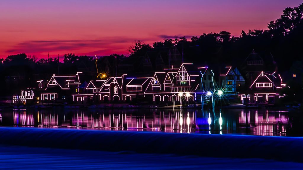 Boathouse Row di Philadelphia illuminata al crepuscolo, con le storiche casette delle società di canottaggio riflesse sulle calme acque del fiume Schuylkill